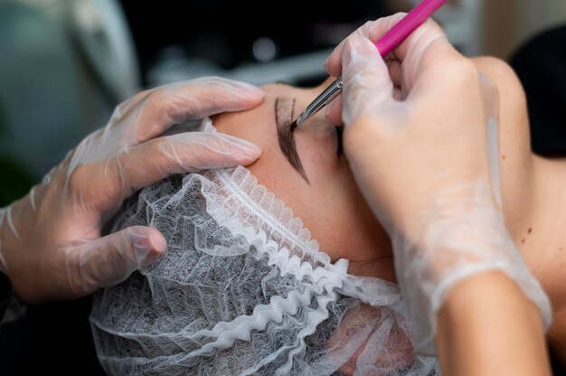 Esteticista realizando procedimento de microblading em uma mulher em um salão de beleza