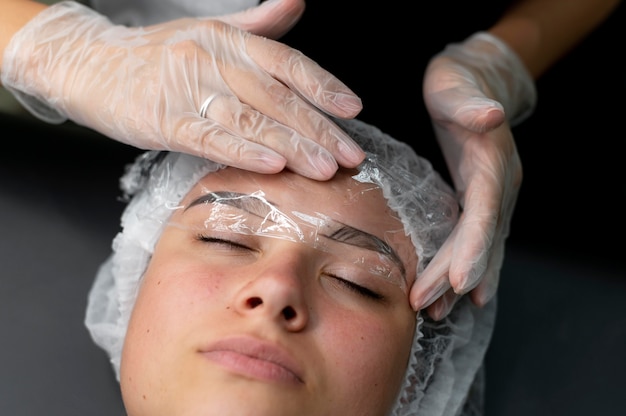 Esteticista realizando procedimento de microblading em uma mulher em um salão de beleza