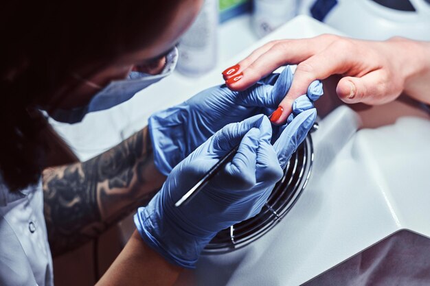 Esteticista trabalhando com um cliente em um salão de beleza, aplicando esmalte colorido. Procedimento de manicure em um salão de beleza