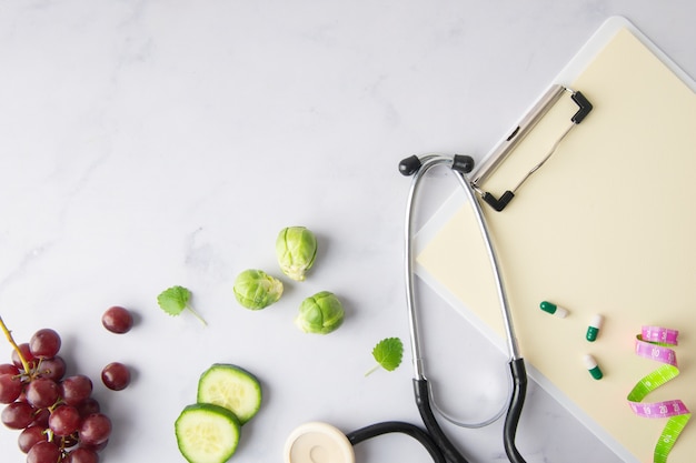 Foto grátis estetoscópio de vista superior com fatias de pepino e uvas