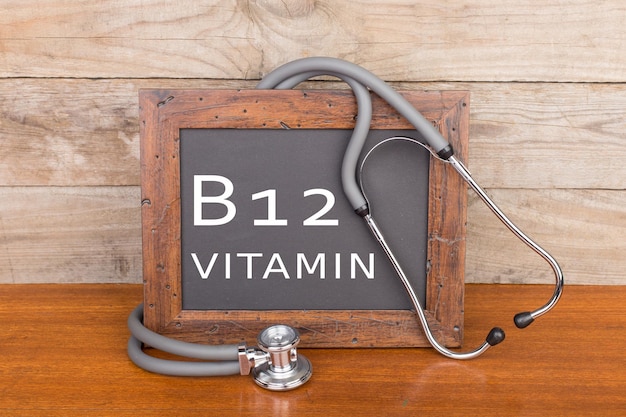 Estetoscópio e quadro-negro com texto vitamina b12 em fundo de madeira Foto Premium