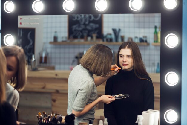 Estilista aplicar cosméticos na linda mulher