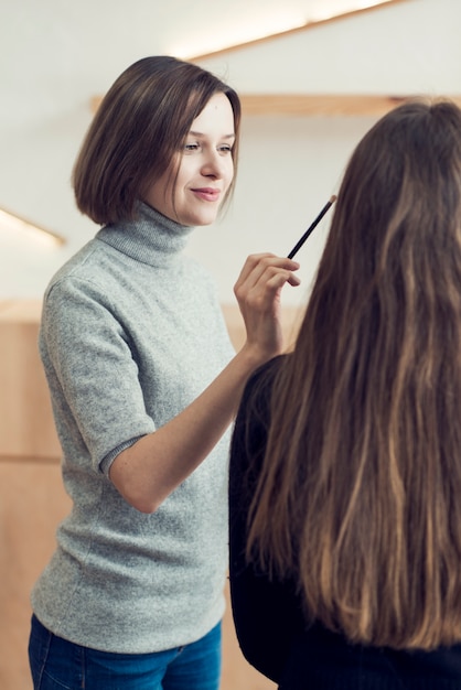 Estilista linda aplicar maquiagem no modelo irreconhecível