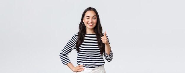 Estilo de vida beleza e moda pessoas conceito de emoções Alegre menina asiática fofa polegar para cima em aprovação pisca encorajando e sorrindo elogiando bom trabalho dizer bem jogado como felicitar com vitória