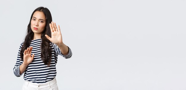 Foto grátis estilo de vida beleza e moda pessoas conceito de emoções mulher irritada se sentindo desconfortável sendo fotografada perguntando desligar a câmera levantando as mãos defensivas protegendo o rosto da lanterna