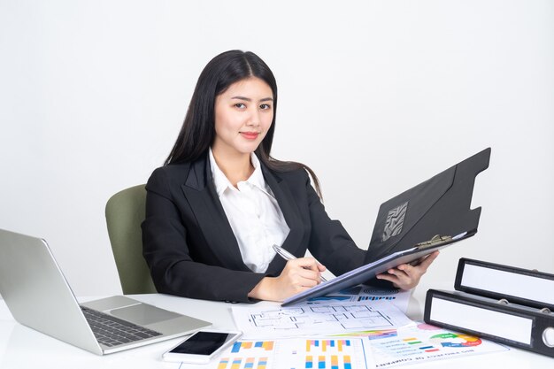 estilo de vida bonito jovem mulher de negócios asiáticos usando computador portátil e telefone inteligente na mesa de escritório