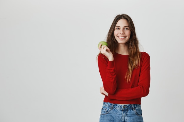 Estilo de vida saudável e conceito de esporte. mulher atraente sorridente comendo maçã