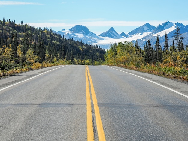 Estrada asfaltada com linhas amarelas e a Geleira Worthington no Alasca