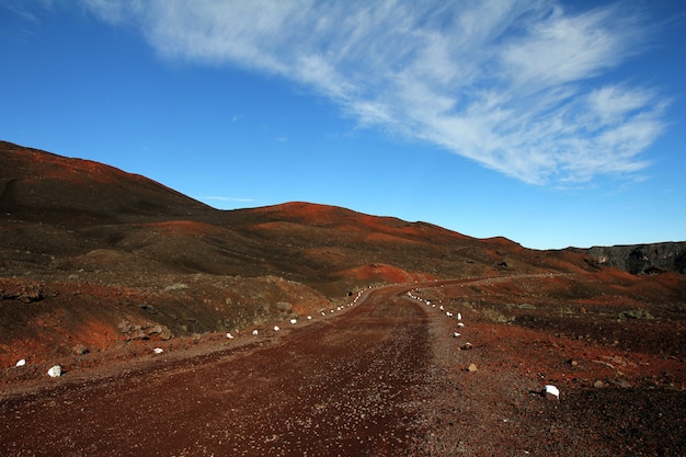 Estrada de terra no meio de colinas desertas, sob um céu azul