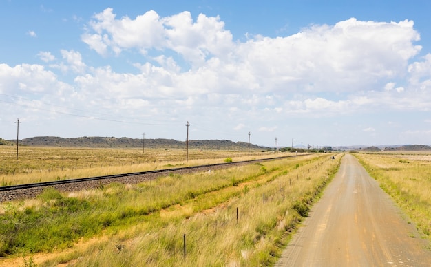 Estrada rural próxima a uma ferrovia em um campo