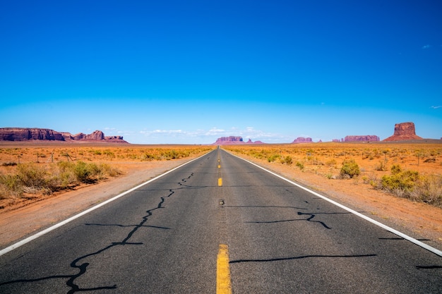 Estrada sem fim que atravessa o Parque Nacional Monument Valley com formações rochosas incríveis