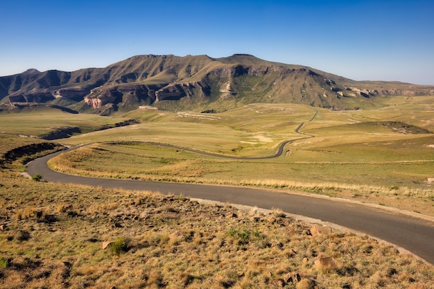 Estrada sinuosa no meio de campos gramados com montanhas à distância na Província do Cabo Oriental