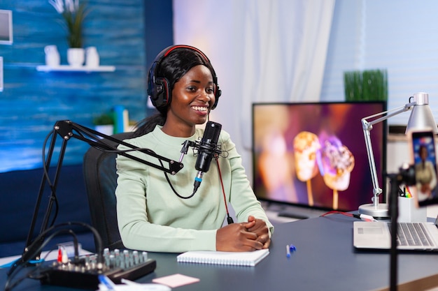 Estrela da mídia social falando para a câmera e gravando um novo episódio do programa. Falando durante a transmissão ao vivo, blogueiro discutindo no podcast usando fones de ouvido.