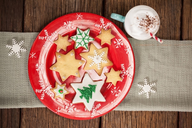 Estrelar biscoitos em forma em uma placa vermelha e copo com creme