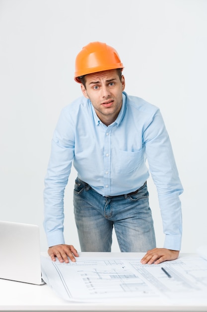 Foto grátis estressado jovem construtor com dor de cabeça ou enxaqueca parecendo exausto e preocupado, isolado no fundo branco, com espaço de cópia.