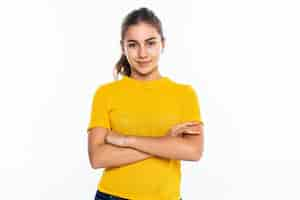 Foto grátis estudante adolescente bonita com expressão confiante, mantém os braços cruzados. retrato do adolescente de sorriso isolado na parede branca.