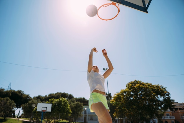 Estudante adolescente feminino jogando basquete no sportsground