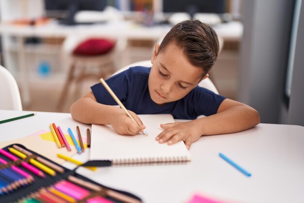 Estudante adorável criança hispânica desenhando no notebook na sala de aula