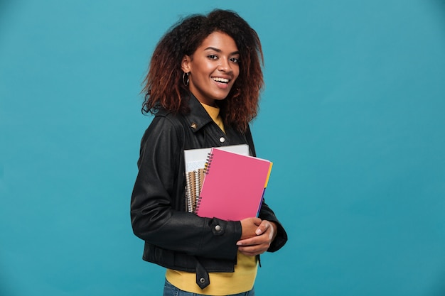 Estudante bela jovem africana feliz segurando cadernos.