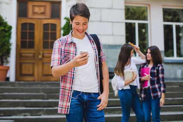 Estudante com telefone e colegas de classe atrás