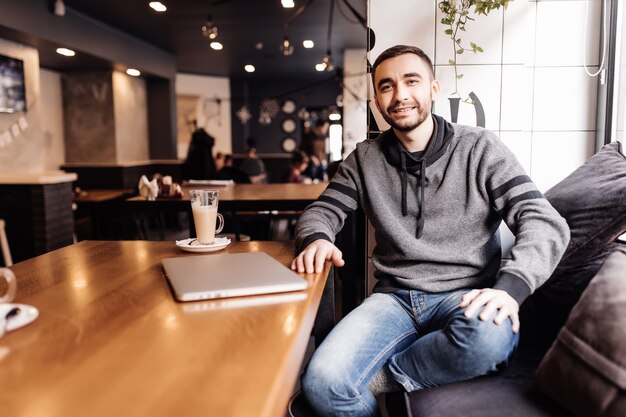 Estudante de jovem com laptop bebe café no café