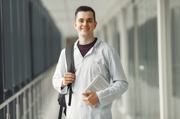 Estudante de medicina com uma mochila está de pé em uma clínica moderna