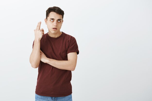 Estudante do sexo masculino atraente descontente e irritado com camiseta vermelha