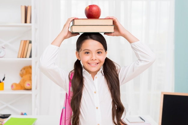 Estudante étnica segurando livros na cabeça