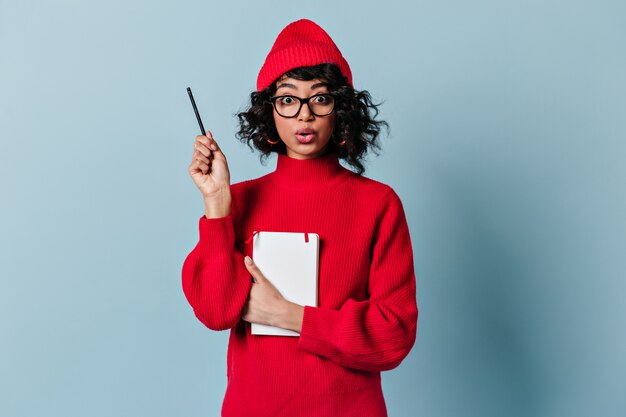 Estudante internacional chocado segurando caneta e caderno