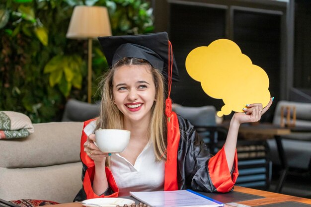 Estudante loira bonita segurando o quadro de ideias e bebendo café