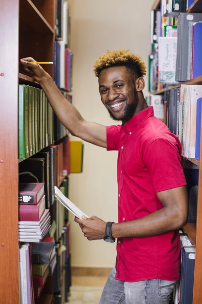 Estudante posando na biblioteca sorrindo para a câmera