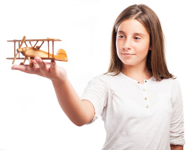 Estudante que mostra um avião de madeira