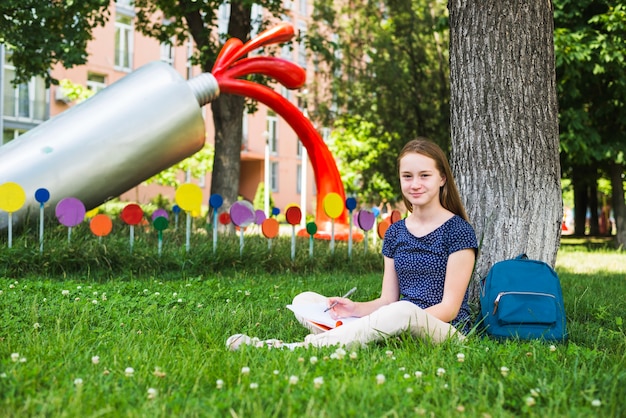 Estudante satisfeito sentado na grama com notas