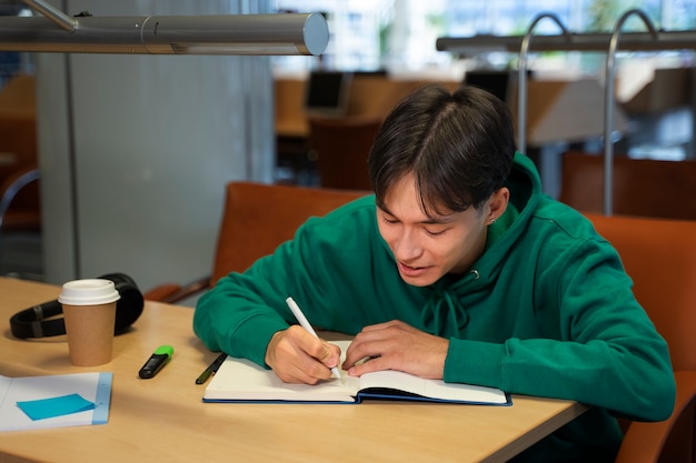 Estudante sorridente de tiro médio escrevendo