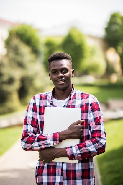 Estudante universitário afro-americano com laptop em um dia ensolarado na rua da cidade