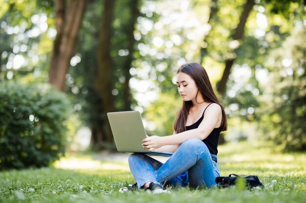 Estudante universitário asiática ou mulher freelance que usa o laptop em escadas no campus universitário ou no parque moderno. Tecnologia da informação, educação ou conceito de negócios casuais.