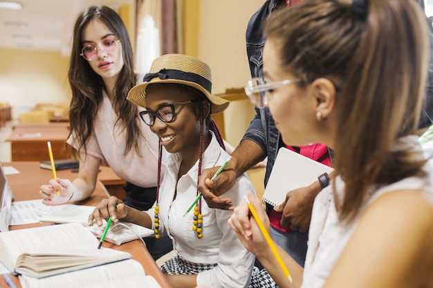 Estudantes alegres sentados à mesa e estudando