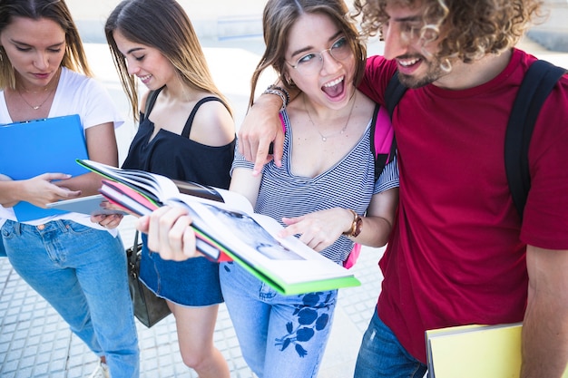 Estudantes animados com pé de livro na rua