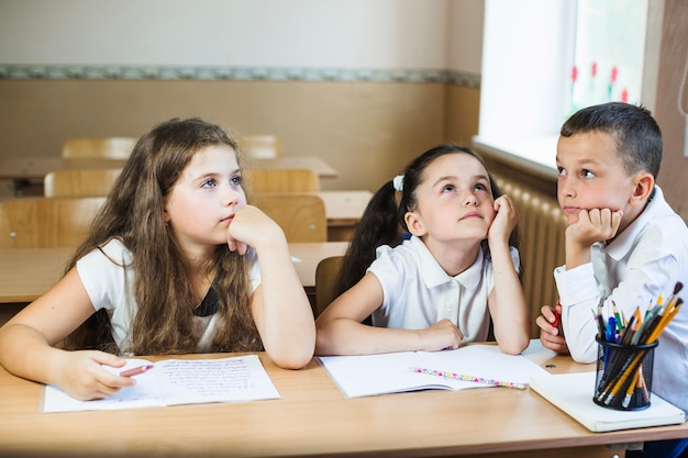 Foto grátis estudantes apoiados nas mãos pensativamente