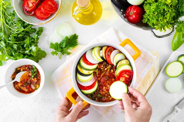 Etapa 3 Vegetais diferentes Uma dieta saudável Ingredientes para assar Ratatouille de legumes em um fundo branco Mãos no quadro Vista superior