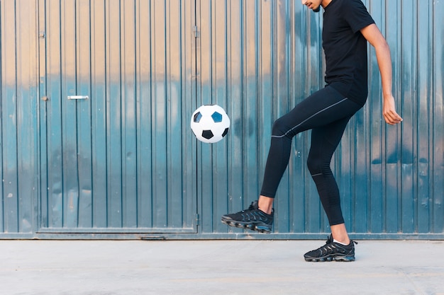 Étnico homem jogando futebol na rua