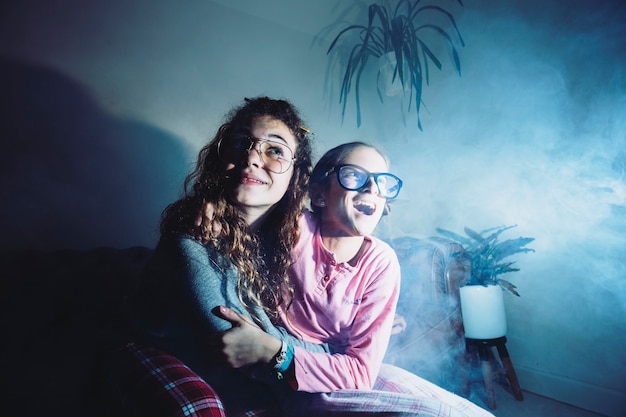 Excited girls in smoke watching tv