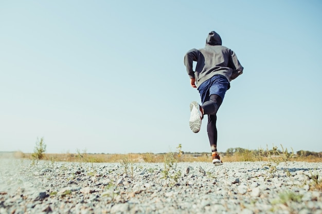 Executando o esporte. Corredor de homem correndo ao ar livre na natureza cênica. Ajuste a trilha de treinamento do atleta masculino musculoso correndo para a maratona. Desportivo cabe homem atlético malhando em roupas de compressão em sprint