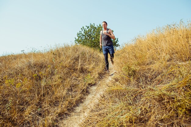 Executando o esporte. Corredor de homem correndo ao ar livre na natureza cênica. Ajuste a trilha de treinamento do atleta masculino musculoso correndo para a maratona.