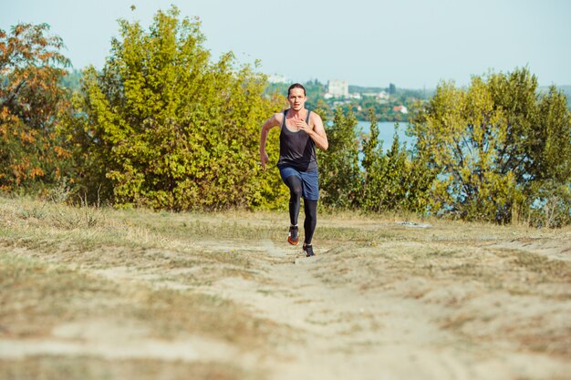 Executando o esporte. Corredor de homem correndo ao ar livre na natureza cênica. Ajuste a trilha de treinamento do atleta masculino musculoso correndo para a maratona.