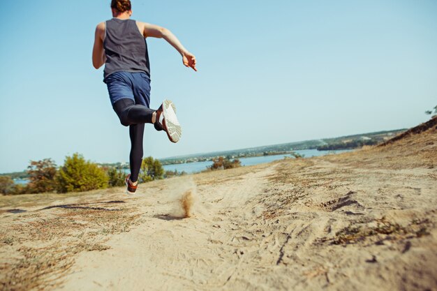 Executando o esporte. Corredor de homem correndo ao ar livre na natureza cênica. Ajuste a trilha de treinamento do atleta masculino musculoso correndo para a maratona.