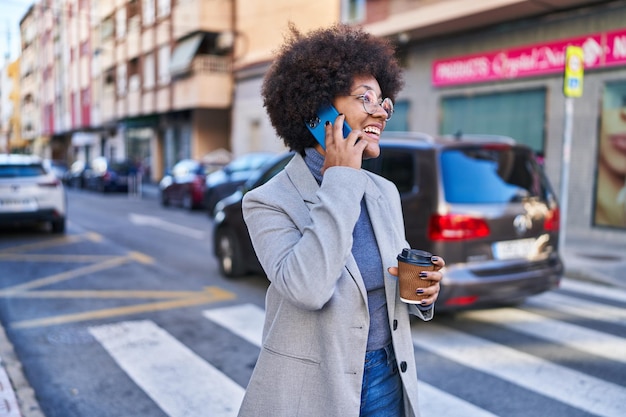 Foto grátis executiva afro-americana falando em smartphone tomando café na rua