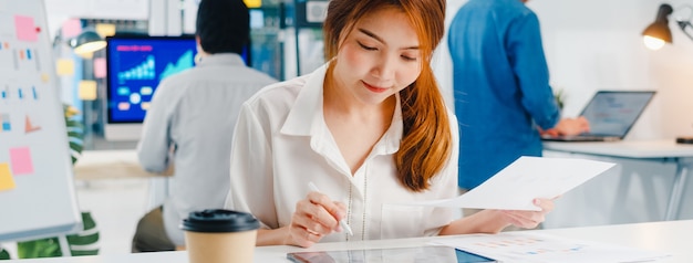 Executivo de sucesso Ásia jovem empresária smart casual wear desenhando, escrevendo e usando a caneta com computador tablet digital pensando em ideias de busca de inspiração processo de trabalho em um escritório em casa moderno.