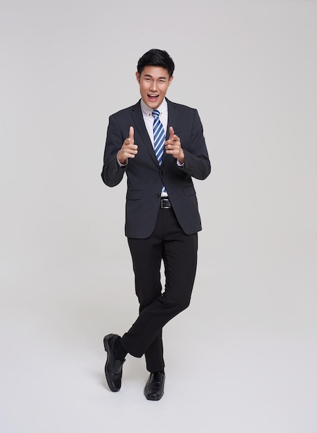 Executivo jovem empresário asiático bonito e confiante em pé no fundo do estúdio