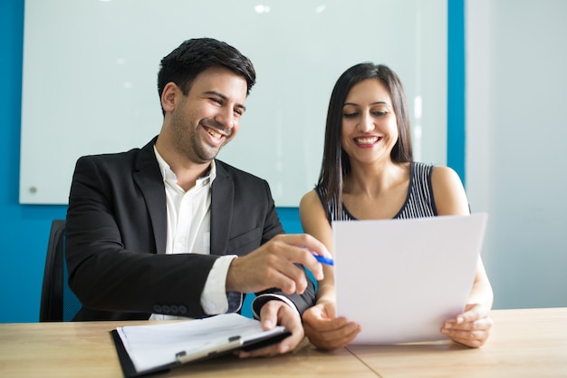 Foto grátis executivos de negócios positivos rindo durante a leitura de contrato